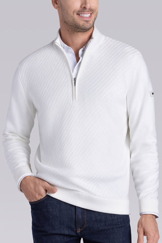 A man wearing a white quarter-zip knit sweater with a subtle textured pattern, paired with a white collared shirt and dark blue jeans, against a solid gray studio background.
