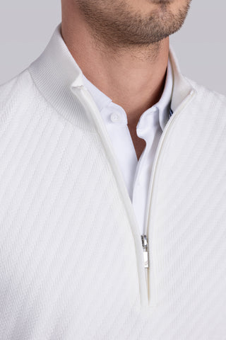 Close-up of a man wearing a white textured quarter-zip pullover over a white collared shirt, against a light gray studio background.