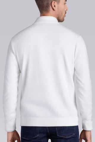 A man viewed from the back wearing a plain white long-sleeve knit top or lightweight sweater, paired with dark blue jeans, against a light gray studio background.