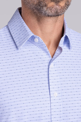 Model wearing Rhythm Santorini Blue 6-Way Knit® short sleeve casual shirt with collar placket, styled with navy shorts.