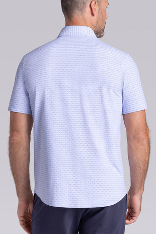 Model wearing Rhythm Santorini Blue 6-Way Knit® short sleeve casual shirt with collar placket, styled with navy shorts.