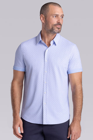 Model wearing Rhythm Santorini Blue 6-Way Knit® short sleeve casual shirt with collar placket, styled with navy shorts.