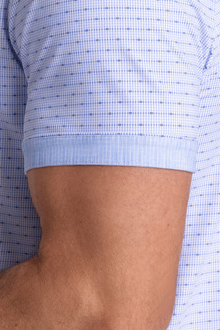 Model wearing Rhythm Santorini Blue 6-Way Knit® short sleeve casual shirt with collar placket, styled with navy shorts.
