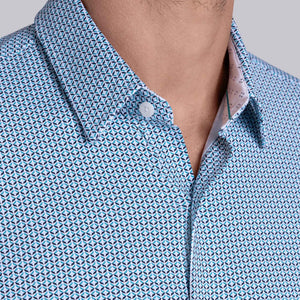 Model wearing Spry Seafoam long sleeve shirt with built in classic collar with geometric print, styled with jeans pants.